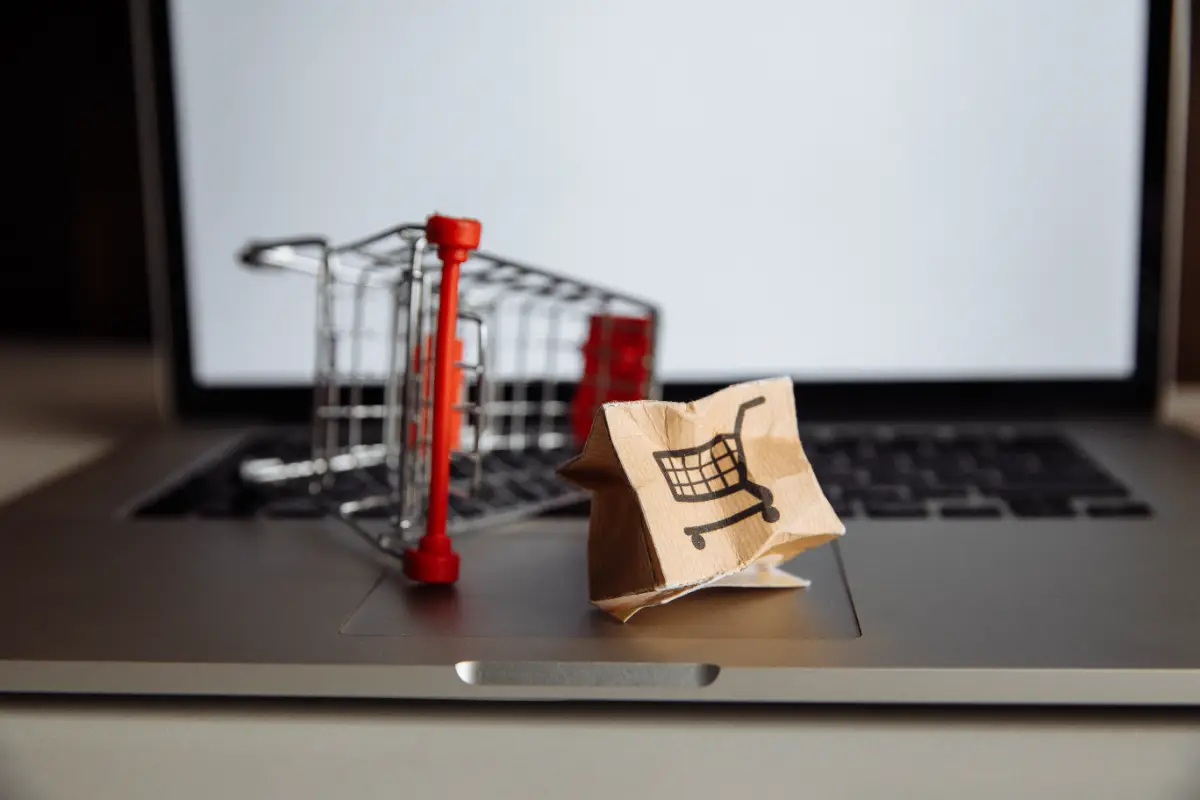 Dizüstü bilgisayar klavyesinde mini alışveriş arabası ve kâğıt alışveriş poşeti ile online pazaryeri satışı
