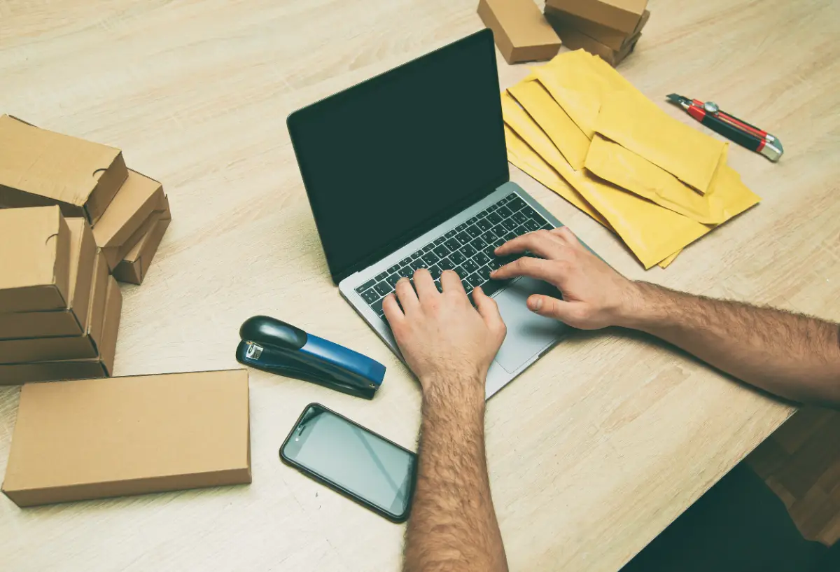 Yurt dışı siparişleri için kargo kutuları arasında dizüstü bilgisayarda çalışan e-ticaret satıcısı